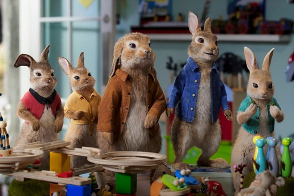 Coelhos usando casacos colorido e em pé em uma sala no filme "Pedro Coelho 2: O Fugitivo"