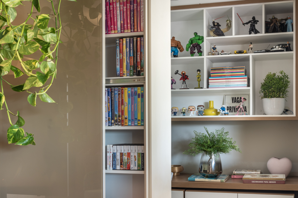 Móvel com compartimento para objetos decorativos e ao fundo uma prateleira com nichos e objetos decorativos
