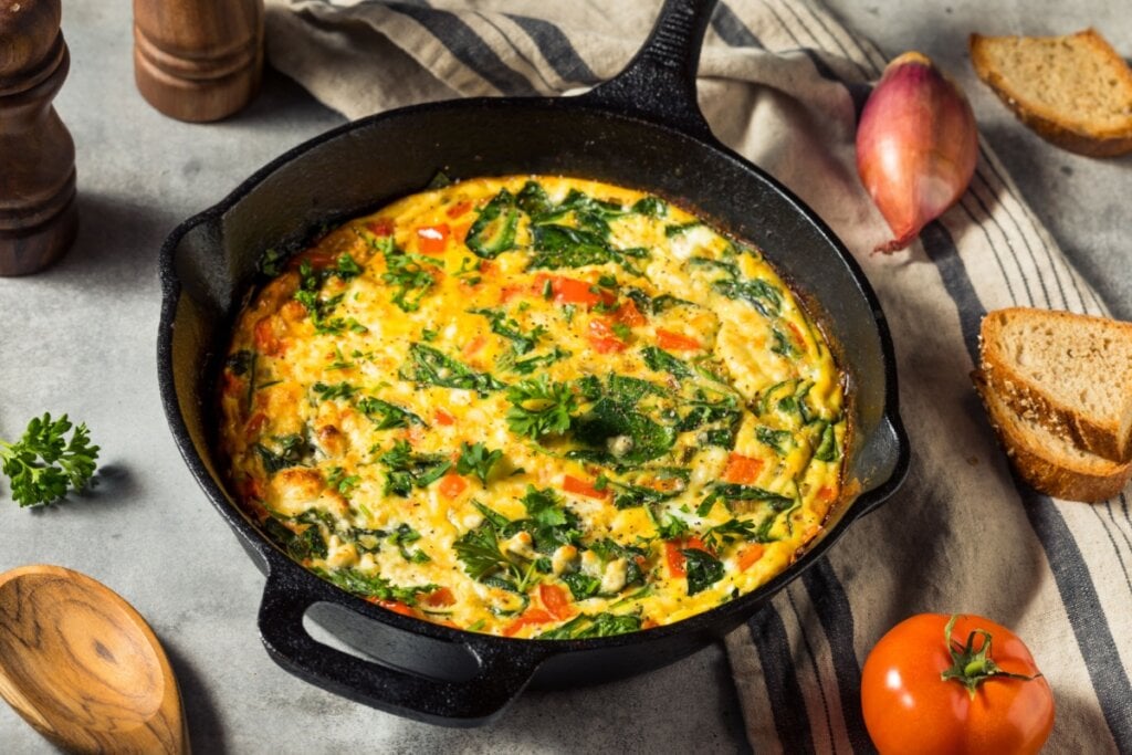 Omelete de espinafre com tomate servido em frigideira de ferro
