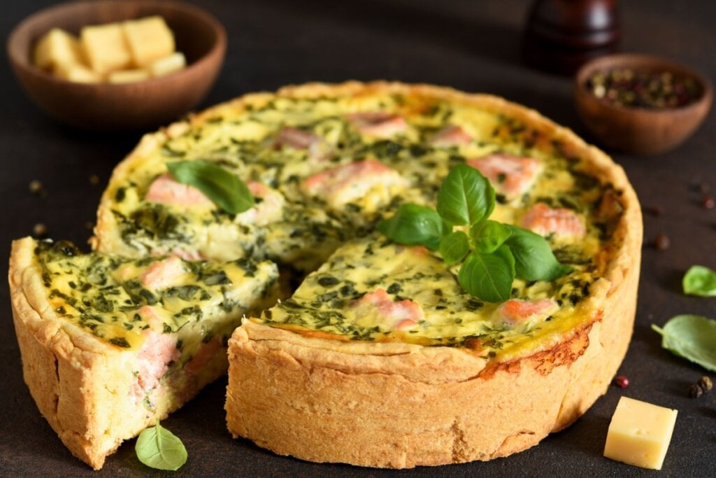 Quiche de salmão com espinafre servido em cima de mesa de madeira