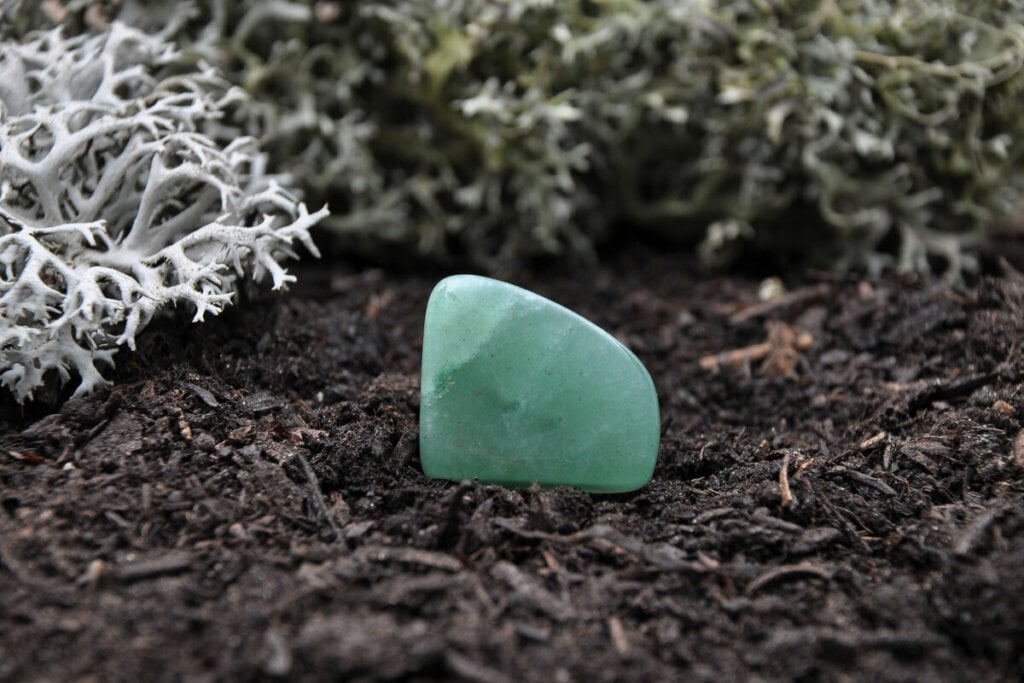 Cristal aventurina verde em cima de uma terra marrom 