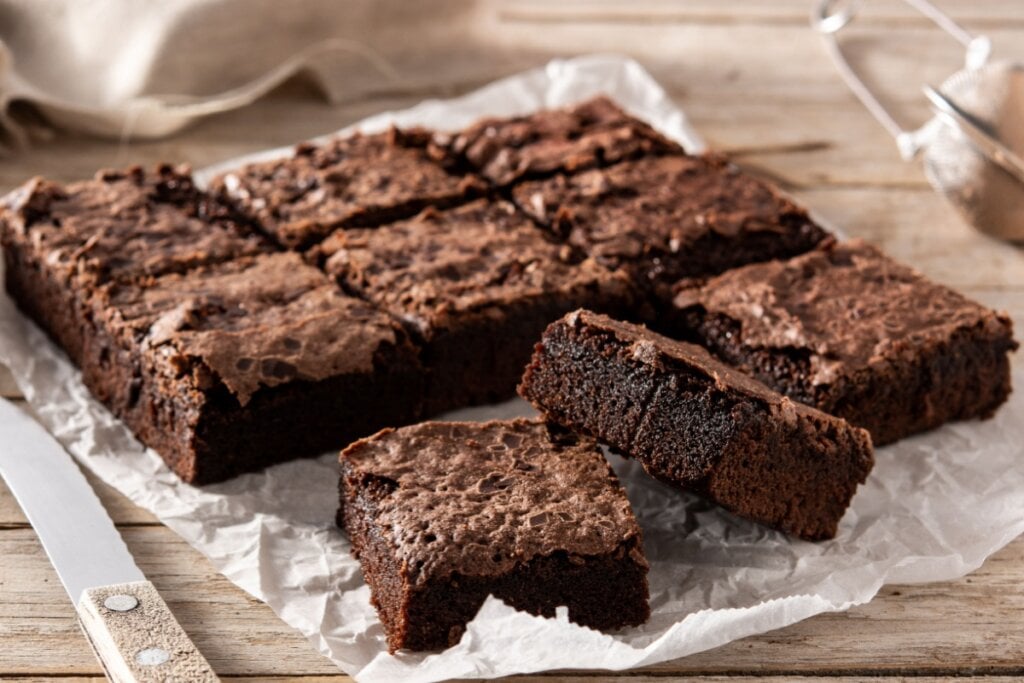 Brownie servido em cima de papel manteiga em cima de mesa de madeira