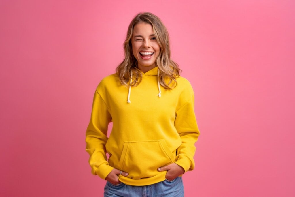 mulher de moletom amarelo em plano de fundo rosa