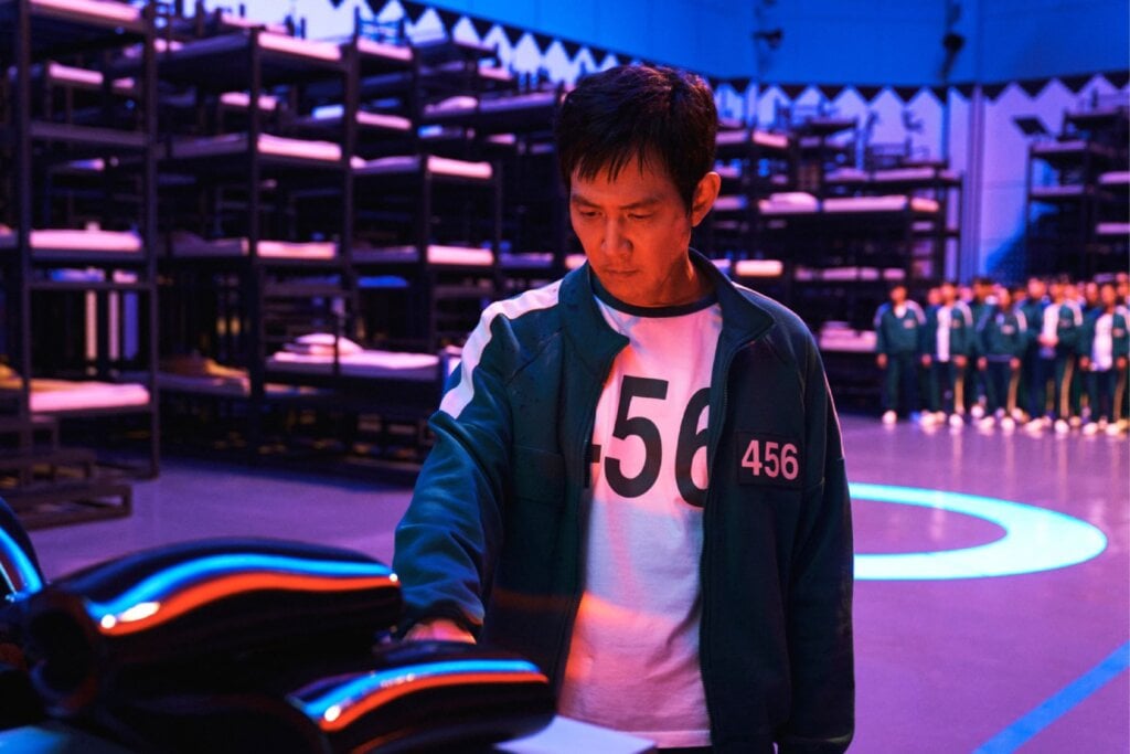 Homem usando um uniforme verde, com a numeração "456", colocando a mão em um objeto de metal