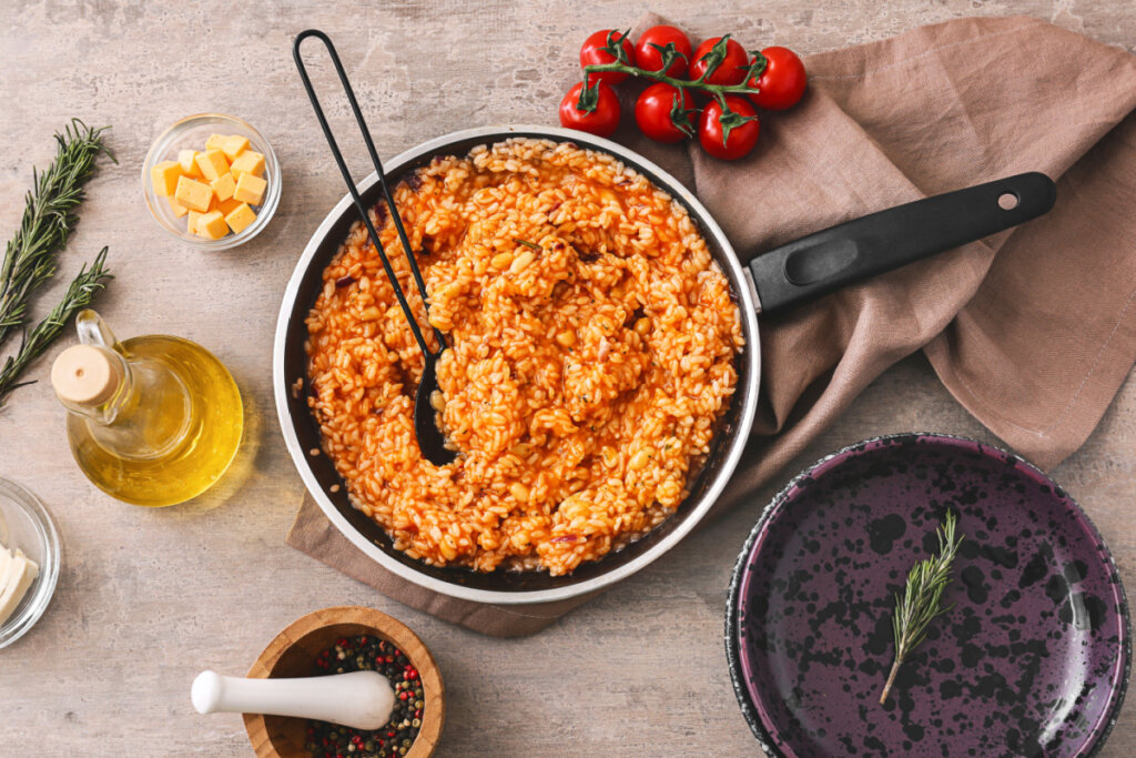 Frigideira com risoto de tomate e outros itens sob a mesa