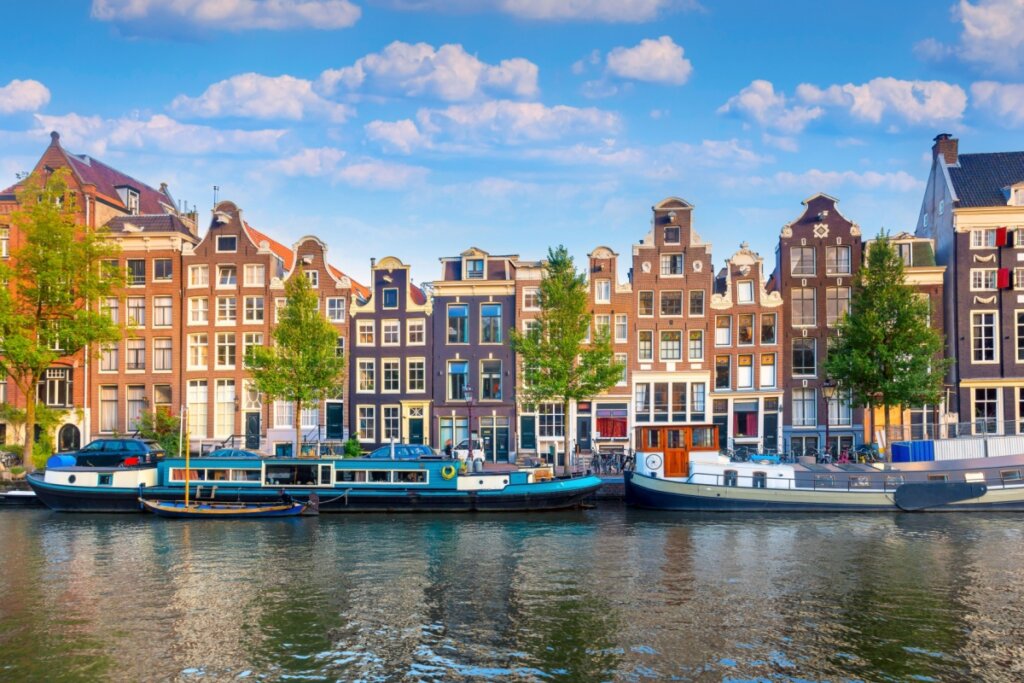 Imagem de um rio com prédios de tijolos ao fundo em Amsterdã