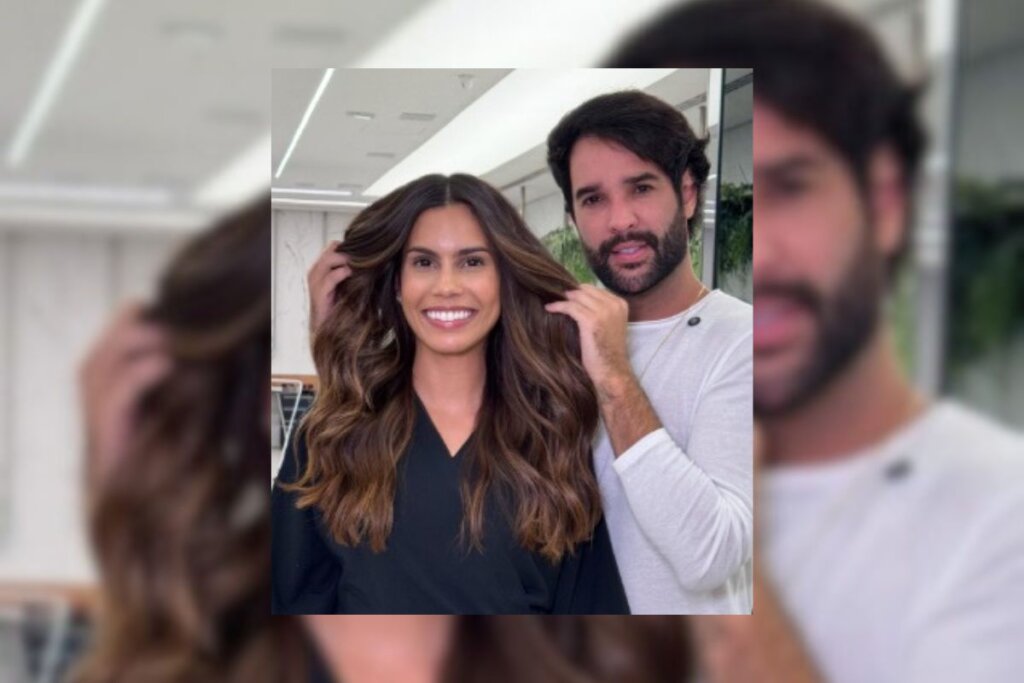 Mulher com cabelo longo e mechas em tom de chocolate sorrindo e um homem do lado segurando algumas mechas do seu cabelo 