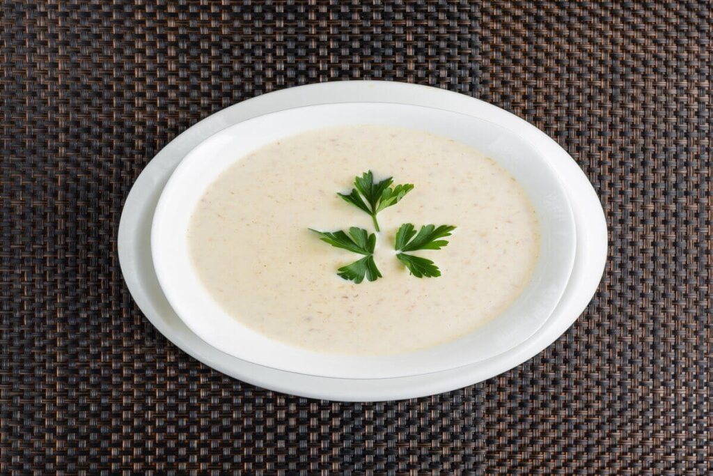 Creme de couve-flor em um prato branco decorado com folhas de coentro