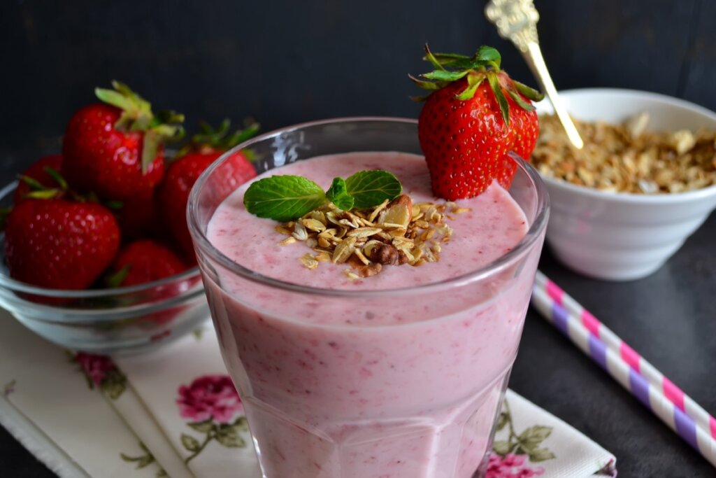 Copo de vidro com vitamina de morango decorado com amêndoas laminadas