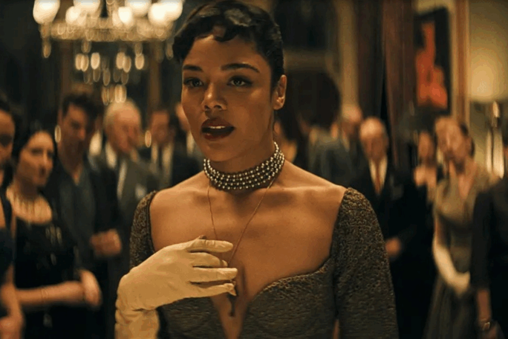 Cena do filme "Hedda" mostrando uma mulher em vestido elegante e colar de pérolas