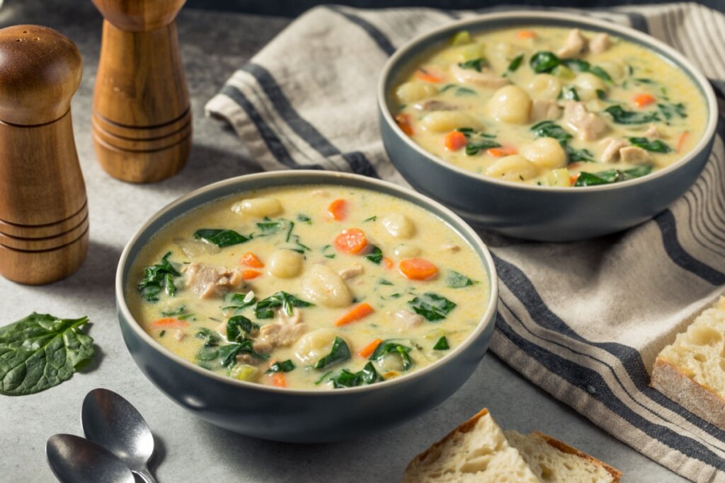 Dois recipientes cinzas com sopa cremosa de nhoque com frango, espinafre e cenoura