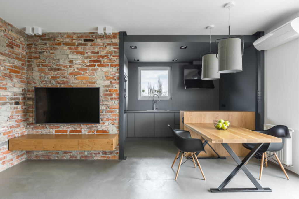Casa com parede com tijolos aparentes com TV e mesa