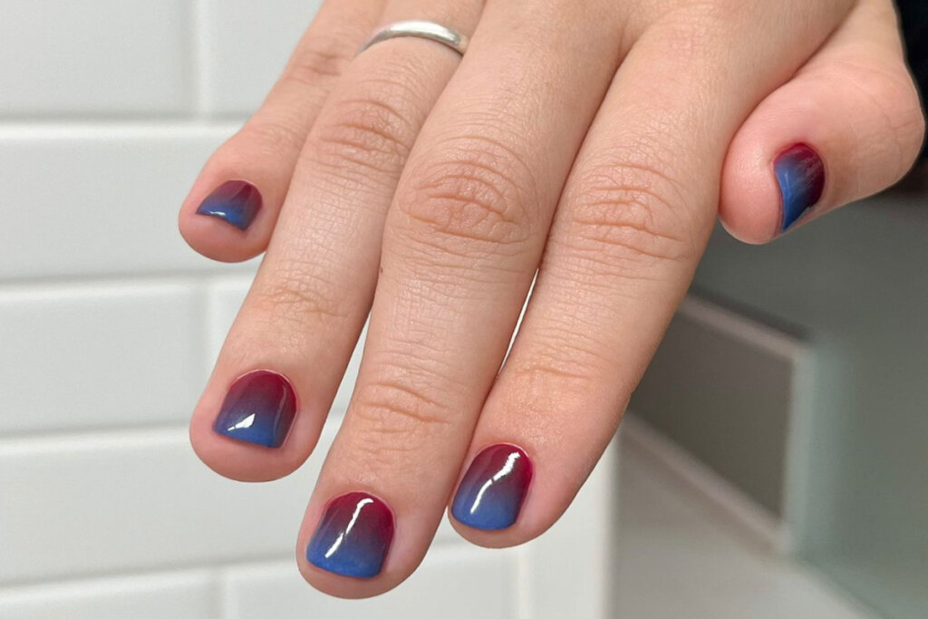 unhas com arte baby boomer, sendo a base mais vermelha e a ponta azulada