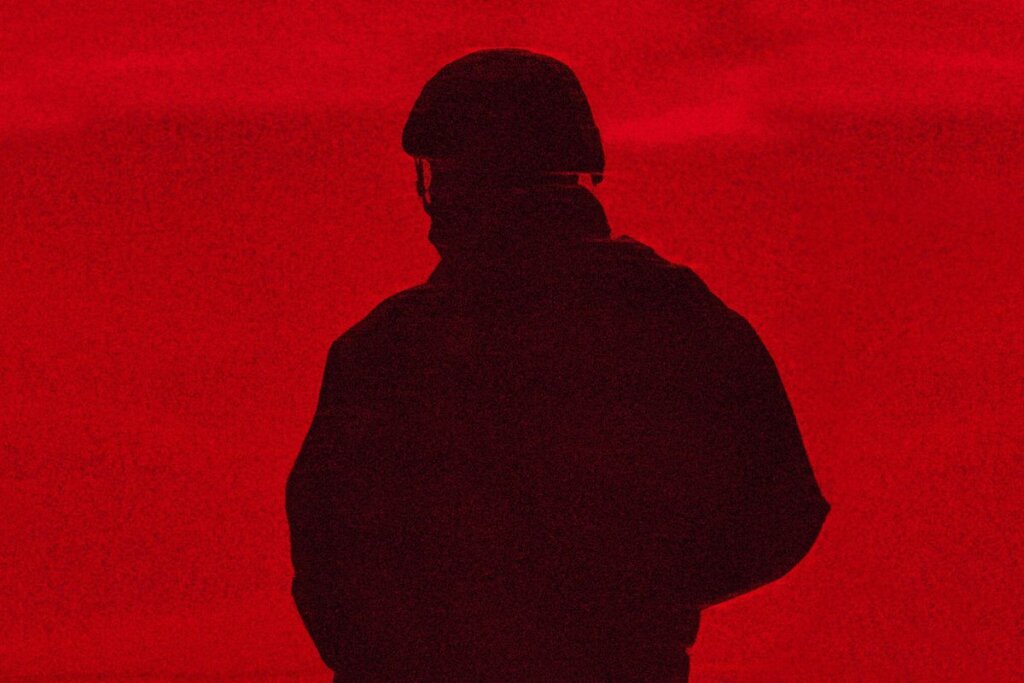 Capa de "Casa de Dinamite" com a sombra de um soldado virado de costas e fundo vermelho 