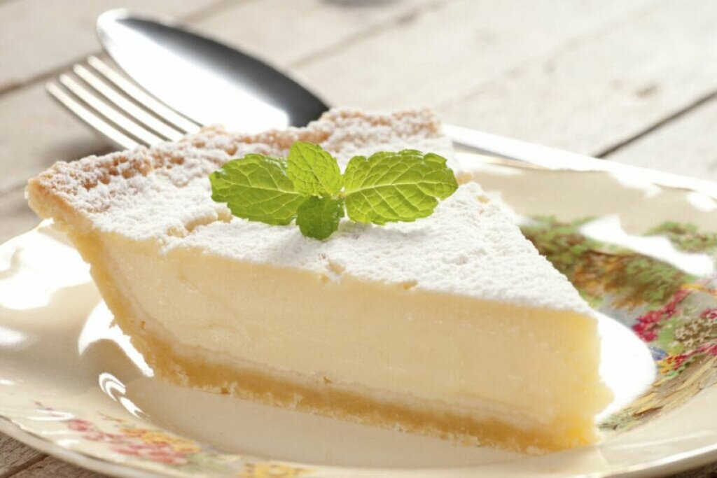 Pedaço de torta de limão decorado com folhas de hortelã em um prato branco