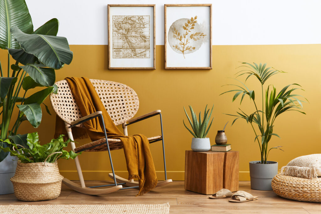 Sala decorada em tons de mostarda e plantas dispostas pelo local