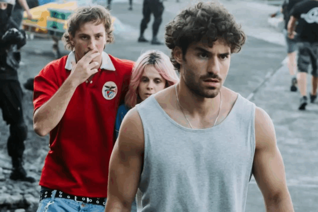 Cena da série “Mar Branco” com três personagens caminhando em ambiente portuário, destacando um homem de camiseta cinza