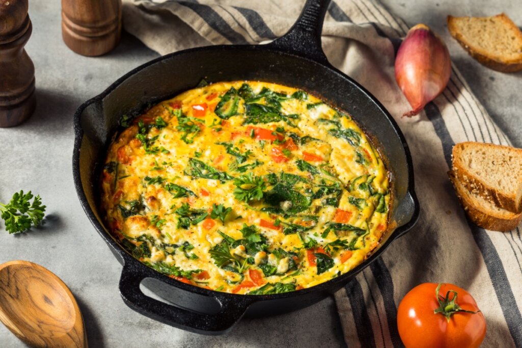 Omelete de espinafre com tomate servido em frigideira de ferro