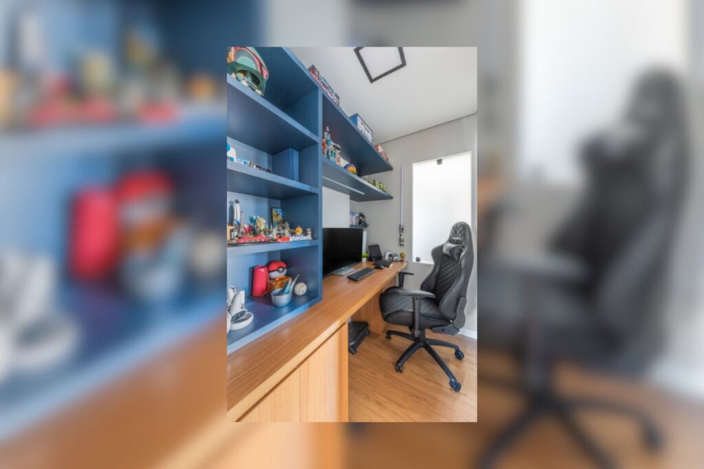 Sala com prateleiras azuis, mesa de madeira e cadeira gamer preta 