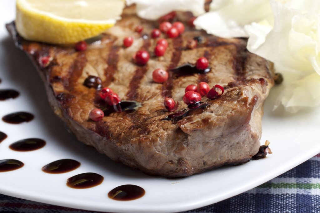 Bife de maminha grelhado com pimenta-rosa e rodela de limão-siciliano servido em prato branco