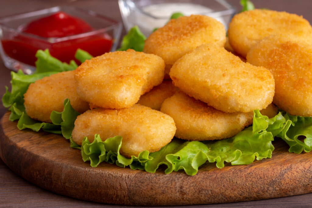 Nuggets em cima de tábua com alface e molhos acompanhando