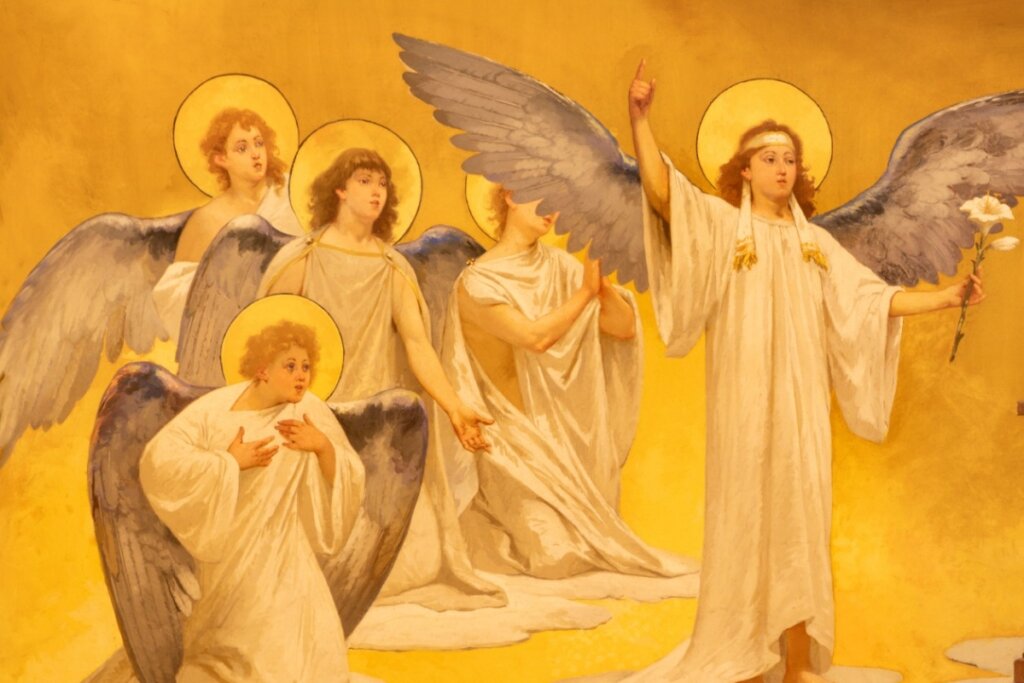 Imagem do arcanjo São Gabriel com roupa branca e asas azuis, segurando flor, com outros anjos menores atrás dele