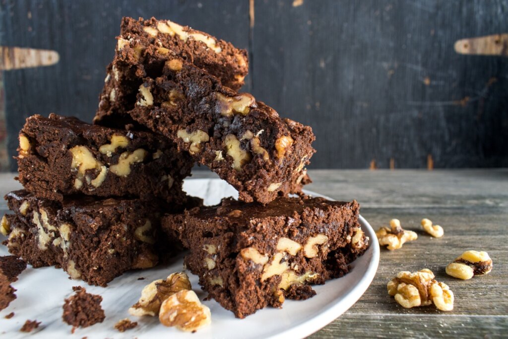 pedaços de brownie de cacau e nozes em um prato branco em uma bancada