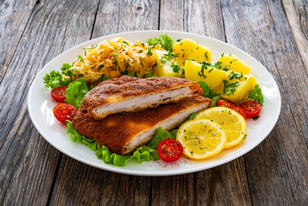 Filé suíno à milanesa em um prato com alface, tomate e batatas cozidas 