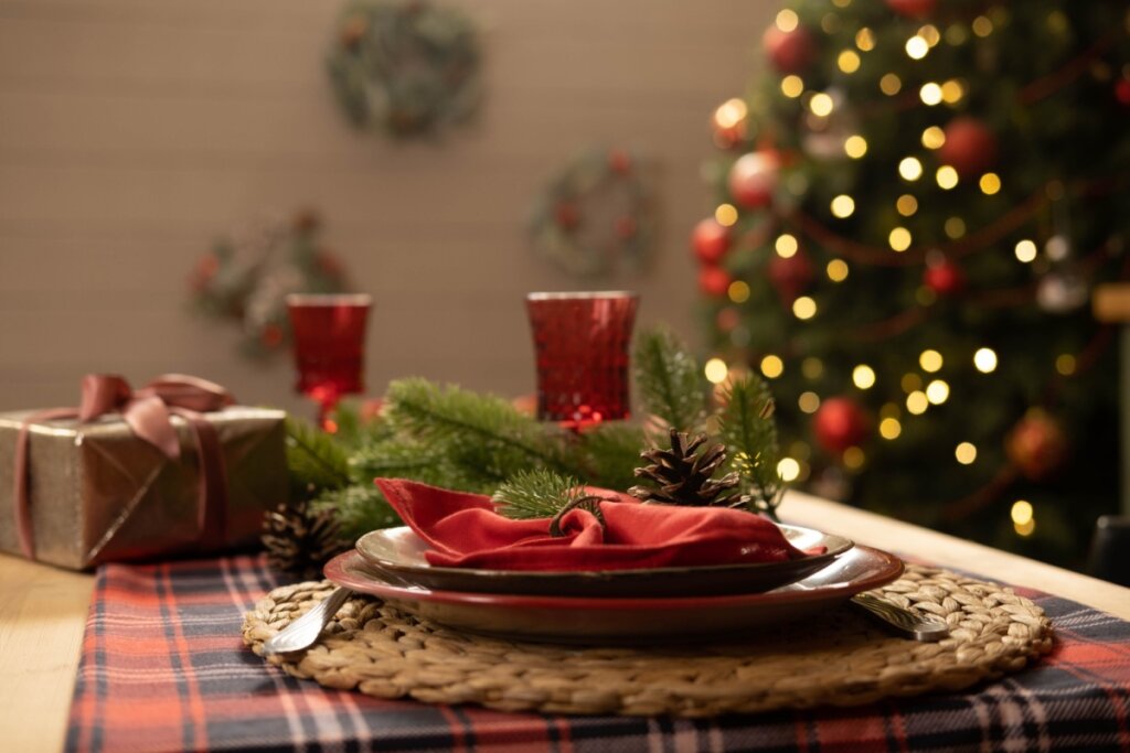 Mesa de Natal com prato marrom, guardanapo vermelho dentro e, ao lado, uma taça vermelha 
