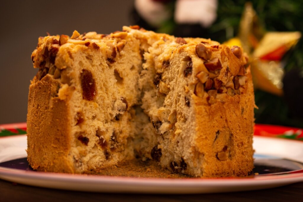 Panetone com castanha-do-pará e damasco servido em prato branco em cima de mesa 