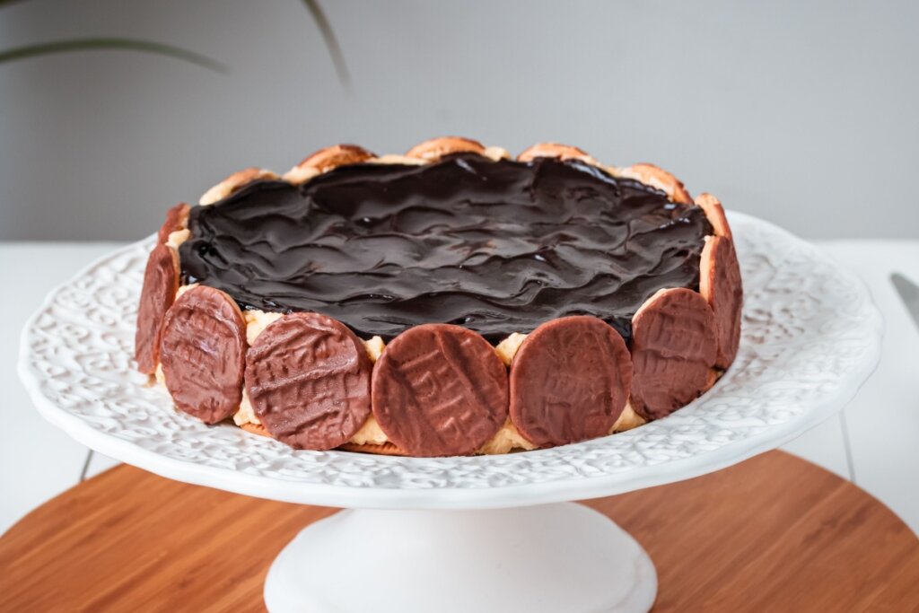Torta holandesa servida em boleira de cerâmica branca em cima de mesa de madeira
