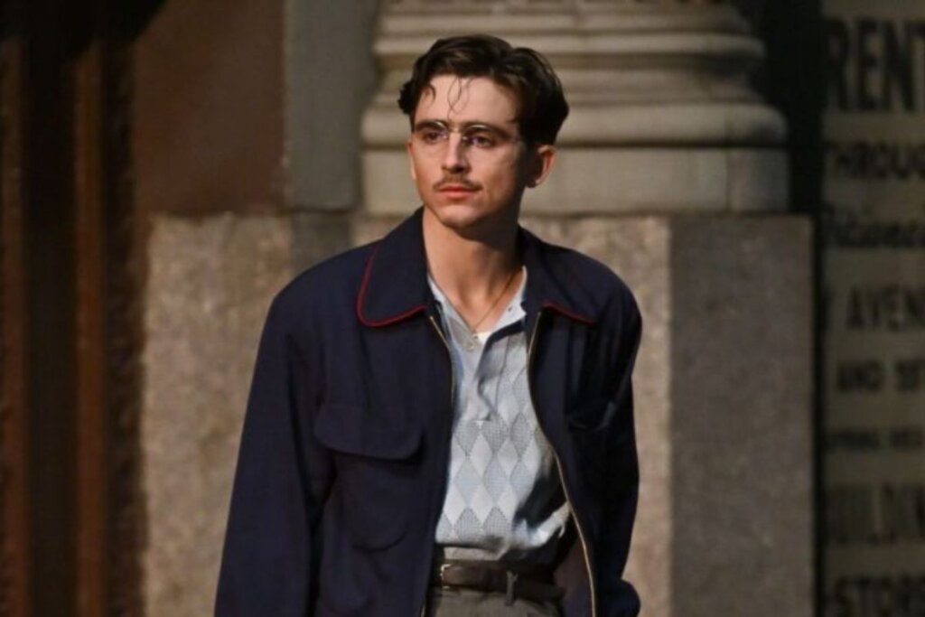 Cena do filme "Marty Supreme", com o ator Timothée Chalamet em pé e olhando para o lado