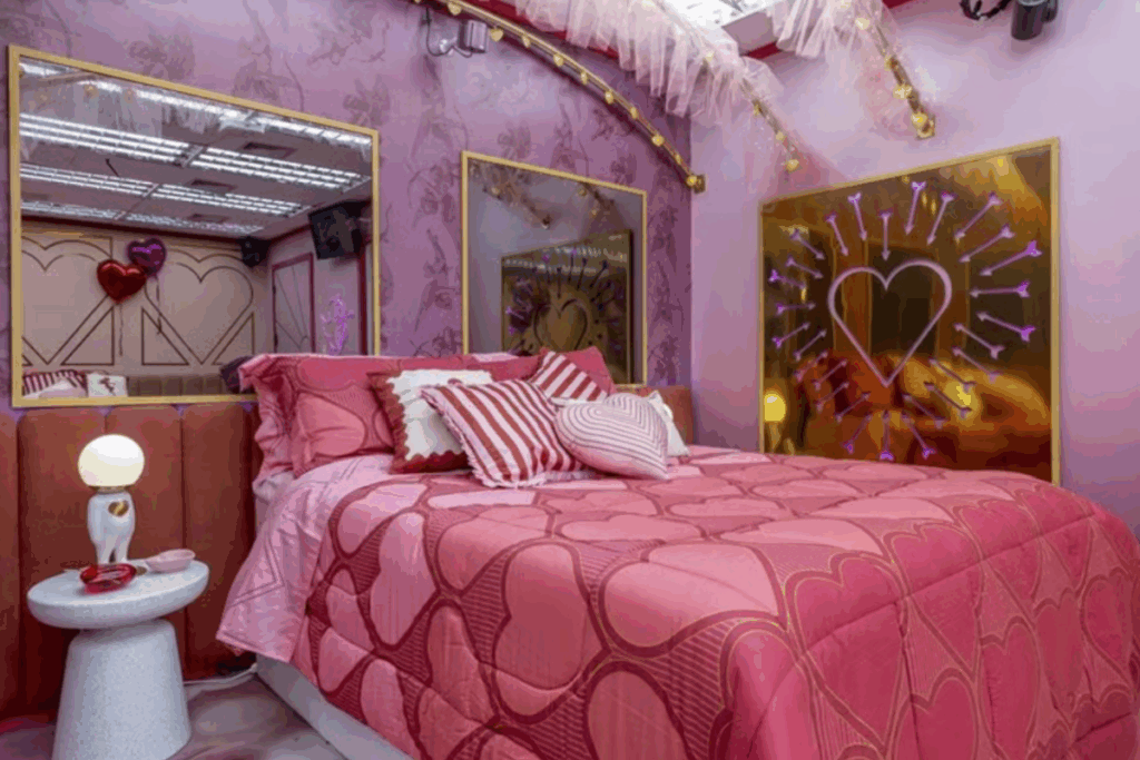 Quarto do BBB 26 com cama de casal, enxoval em tons de rosa e símbolos decorativos