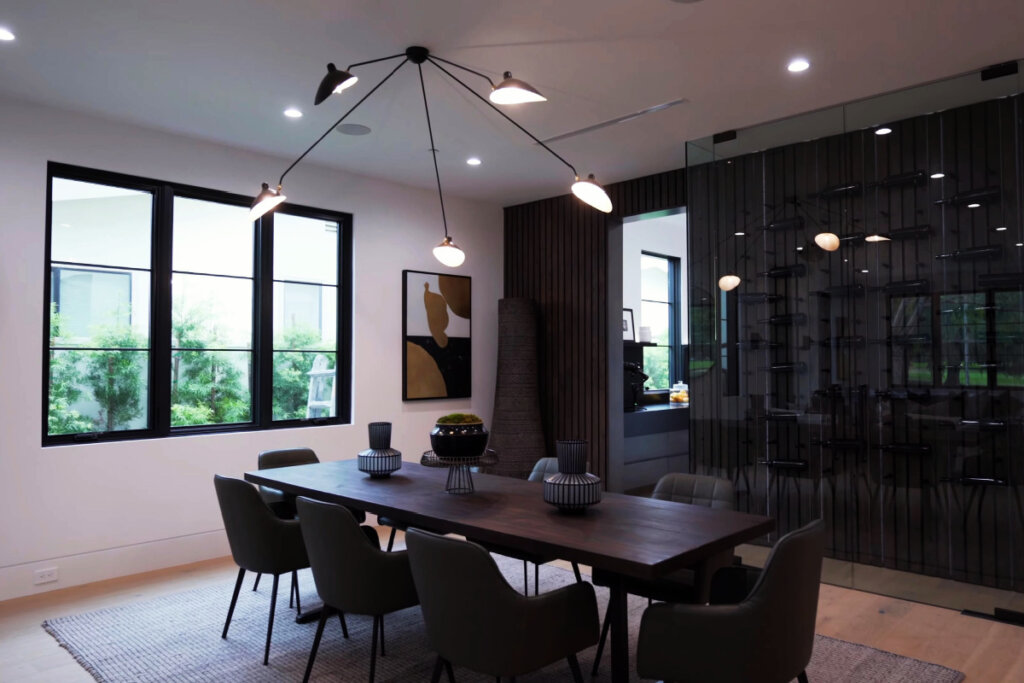 Sala de jantar com mesa de madeira, cadeiras pretas e janela ao fundo