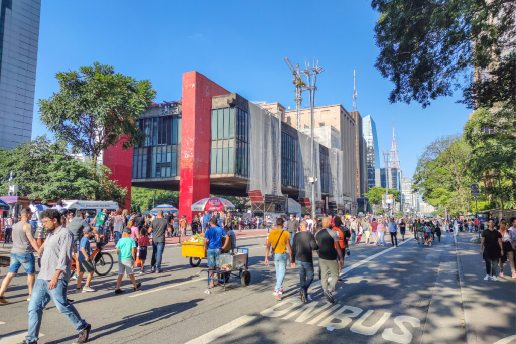 Avenida Paulista com o prédio do MASP no fundo e pessoas andando na rua