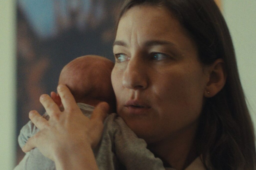 Cena do filme "Mother's Baby", com a protagonista segurando um bebê  e olhando para o lado 