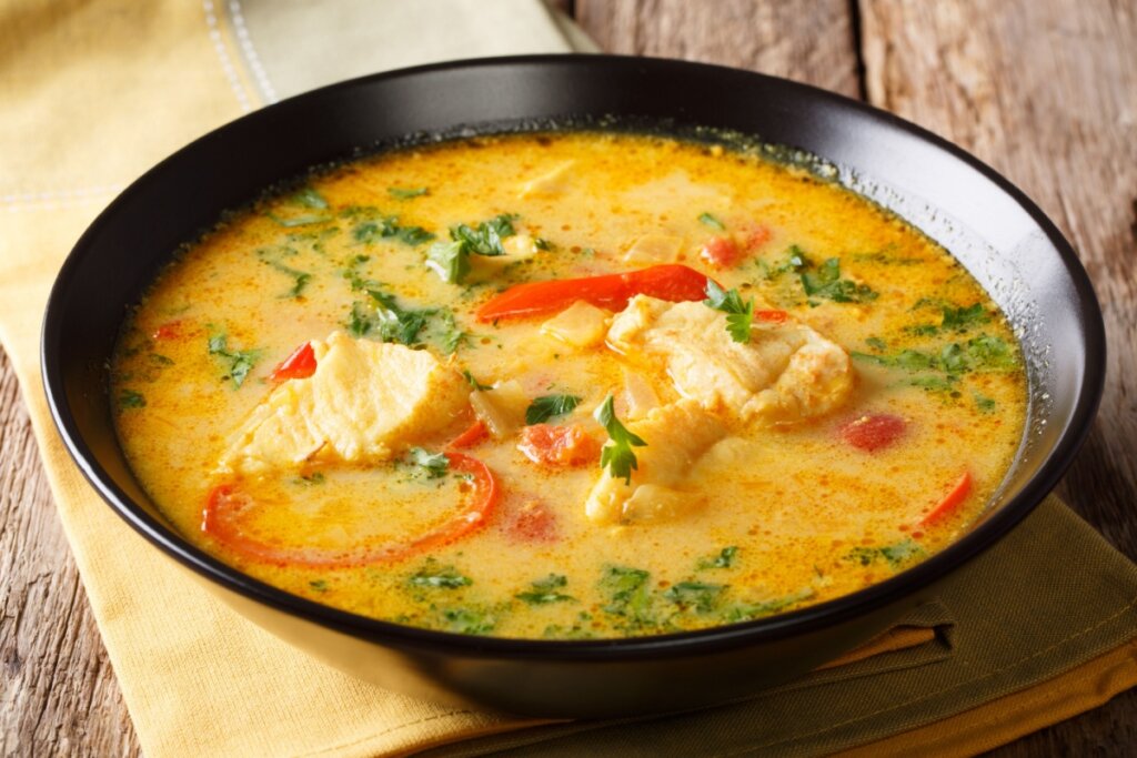 Moqueca em prato preto em cima de pano amarelo