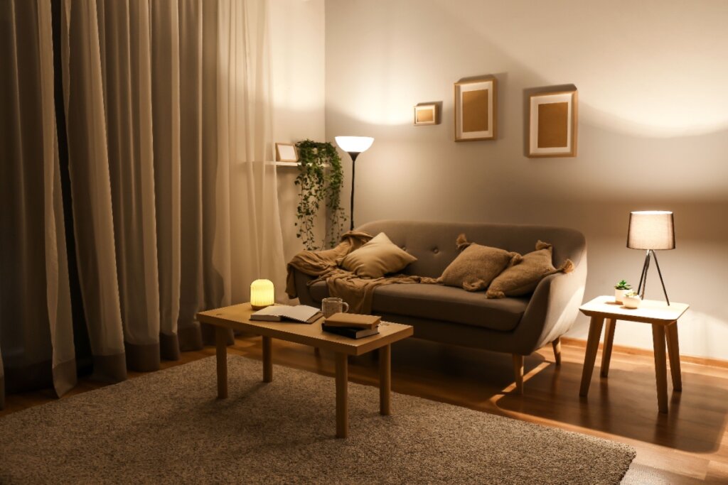 Sala com sofá, mesa de centro, quadros na parede e iluminação baixa e amarelada