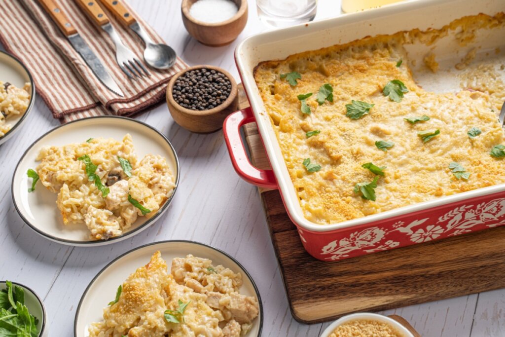 Travessa vermelha e dois pratos ao lado com arroz de forno com frango