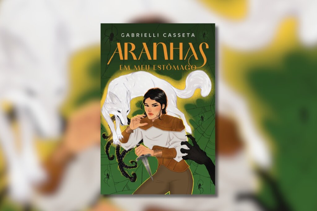 Capa de livro com fundo verde ornamentado e o título "Aranhas em meu Estômago". No centro, uma jovem com trajes de couro segura uma adaga, enquanto a silhueta de um lobo branco surge logo atrás de seus ombros.