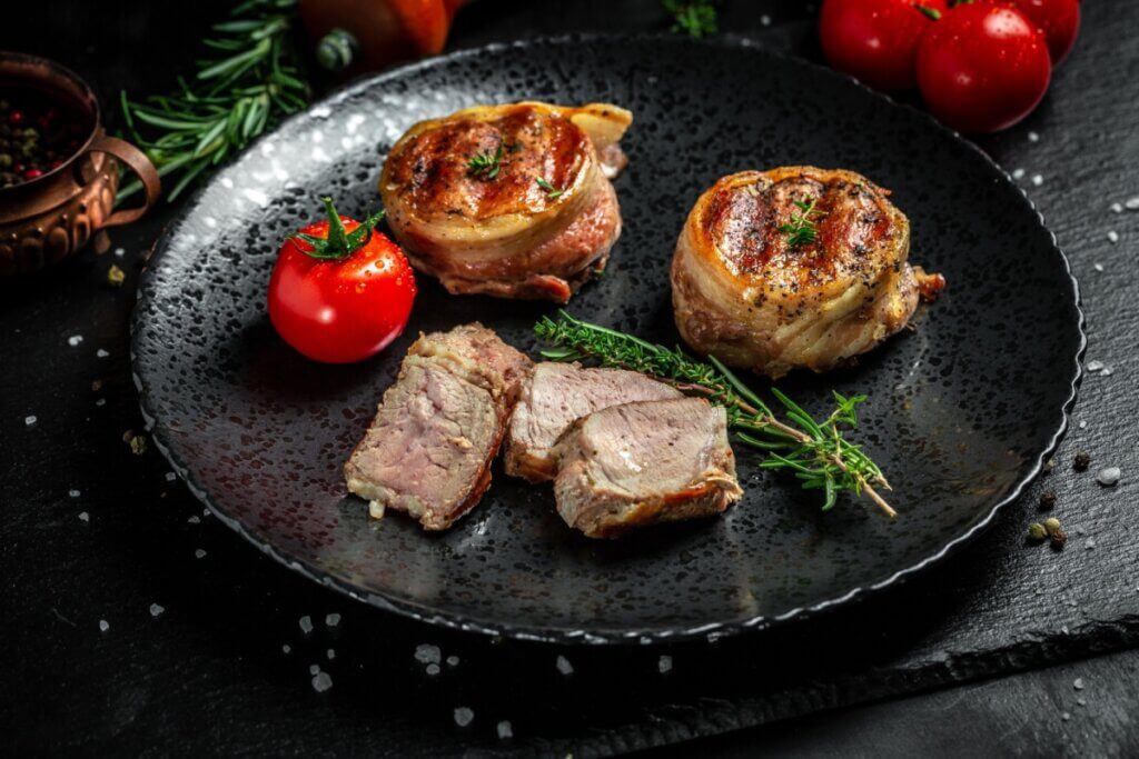 Prato preto com dois medalhões de filé-mignon com bacon