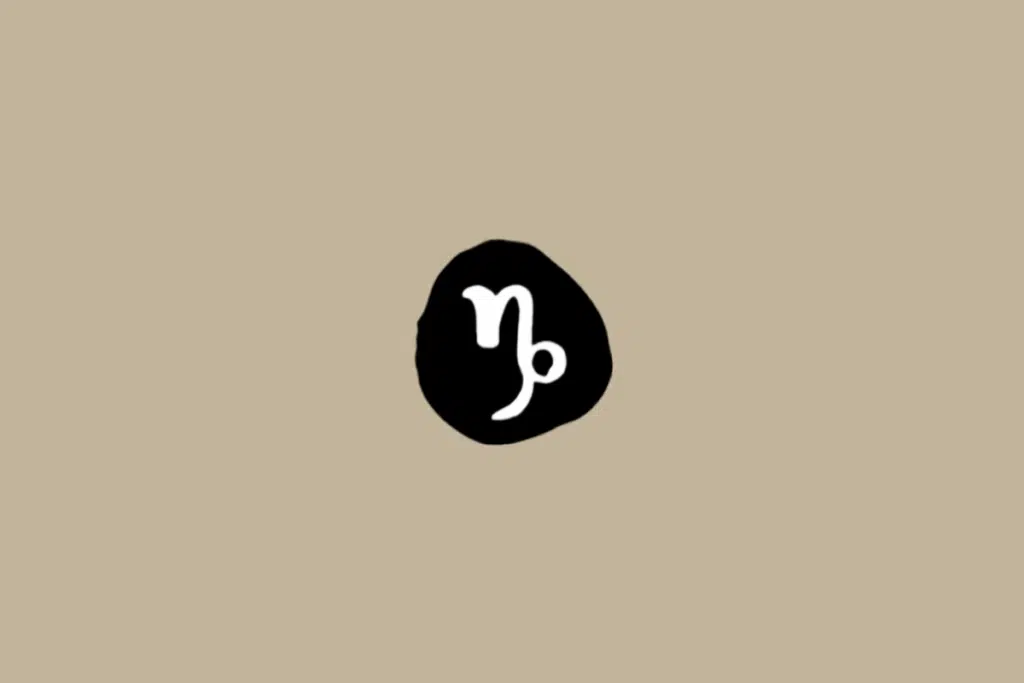 Símbolo do signo de Capricórnio em branco dentro de círculo preto em fundo bege