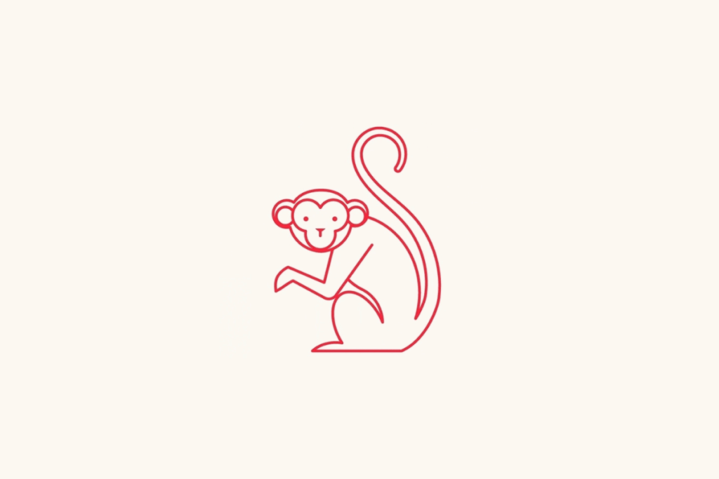 Um macaco sentado de perfil, com o rosto voltado para a frente, pernas dobradas e uma cauda longa e fina que se espirala para cima sobre fundo bege-claro