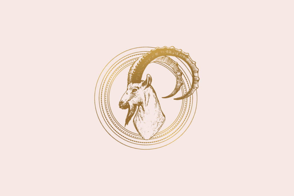 Ilustração do signo Capricórnio: gravura dourada da cabeça de uma cabra de perfil, com um chifre longo curvado em arco que sai do medalhão de anéis dourados finos e pontilhados; em fundo rosa-claro.
